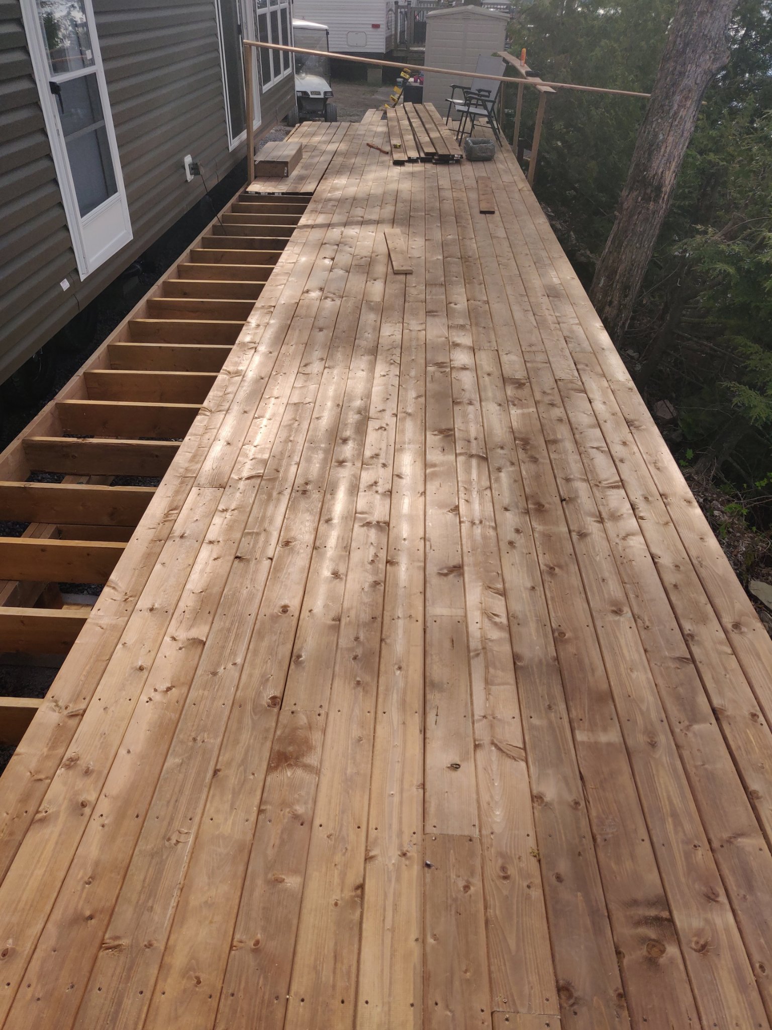 Deck boards being installed over exposed framing beside the home